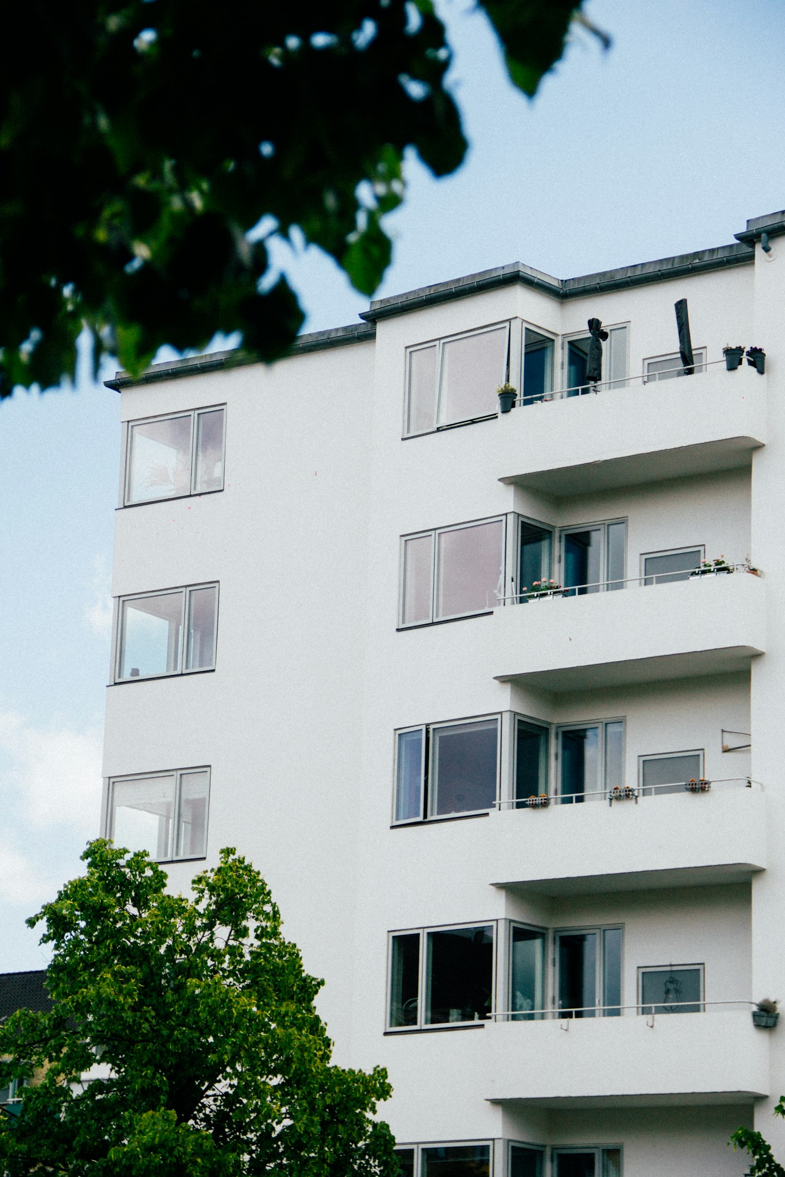 Ağaçlar arasında beyaz apartman cephesi